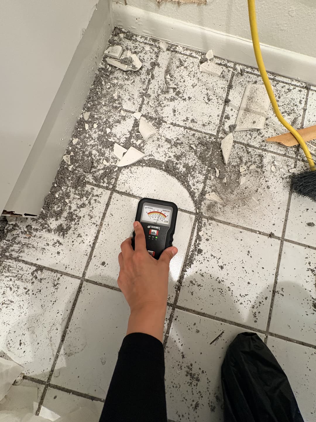 Tramex moisture meter reading elevated levels on bathroom tile floor during water damage assessment in Anaheim