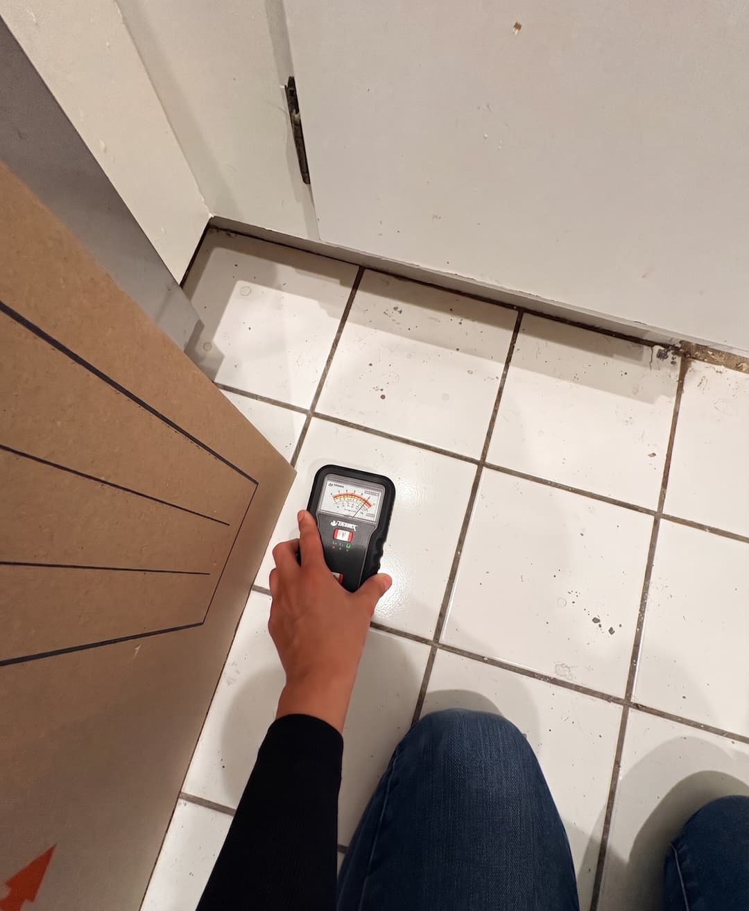 Moisture reading taken on bathroom floor tile near vanity cabinet in Anaheim home