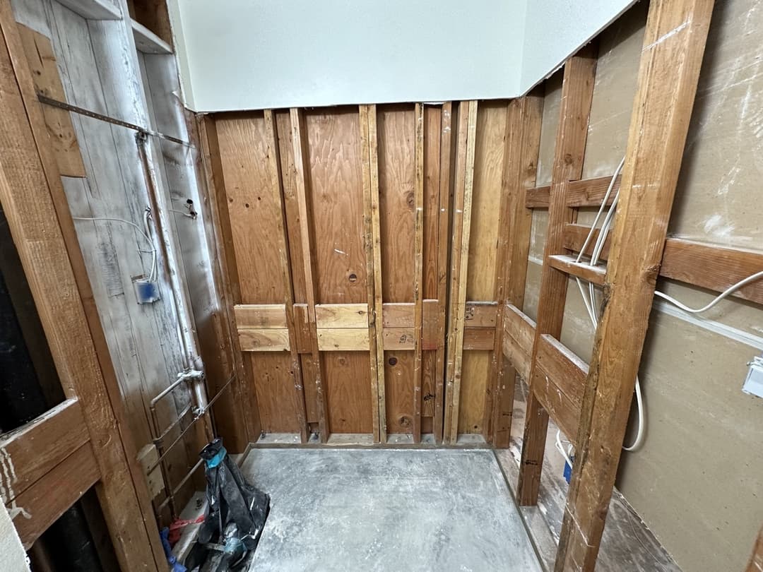 Close-up of exposed wall framing and plumbing after drywall demo at Anaheim water damage restoration project