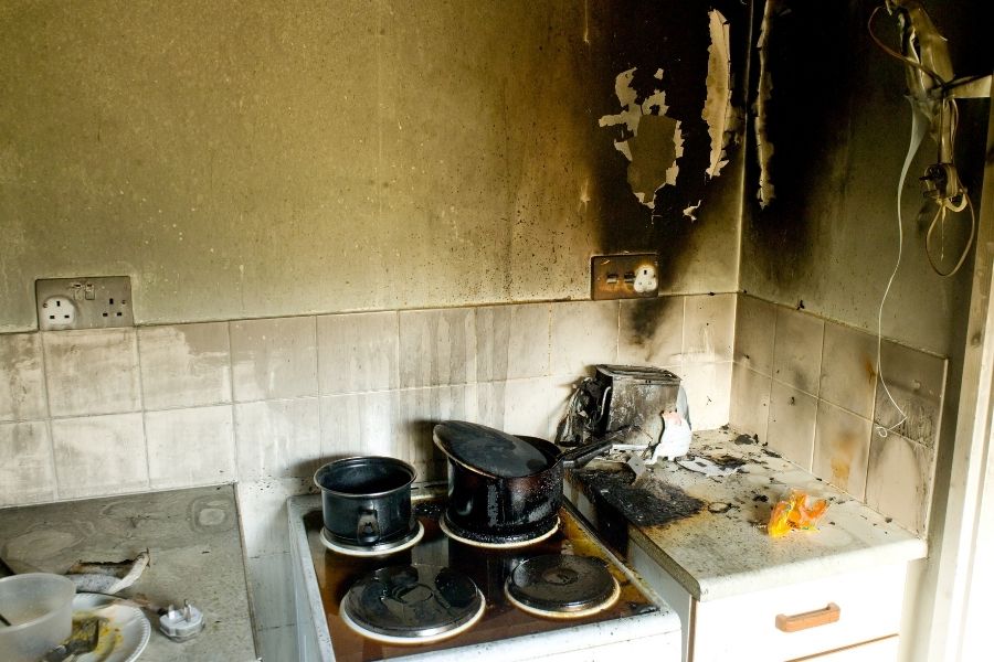 Kitchen showing visible smoke staining on walls and soot residue on countertops after a house fire