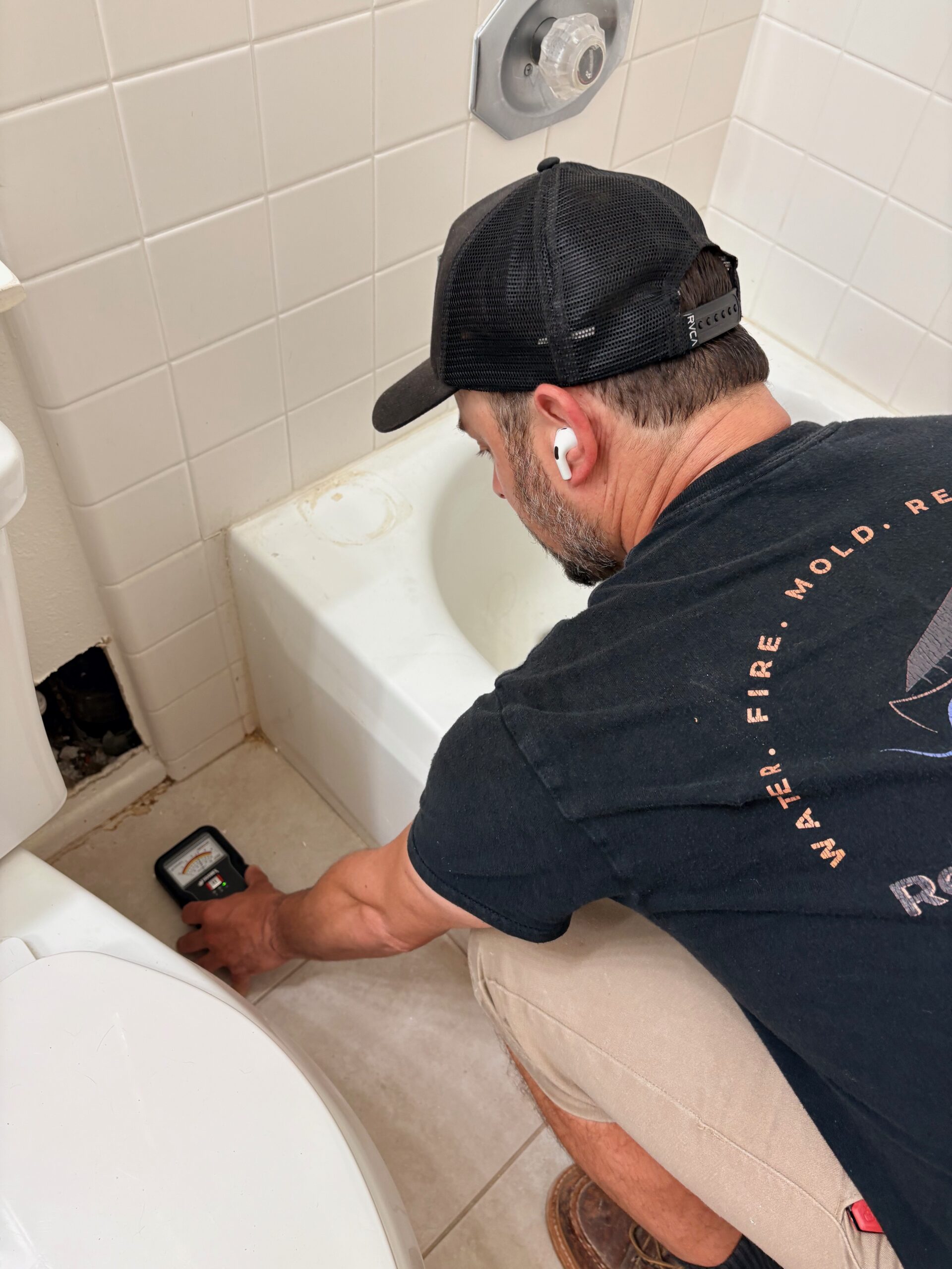 Technician performing moisture check on wall during water damage restoration in Anaheim home