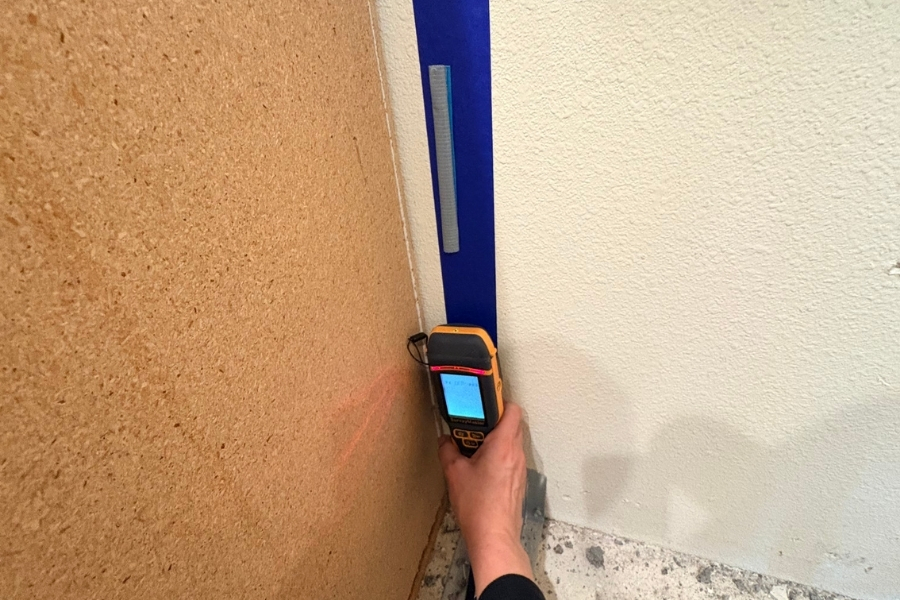 Technician taking a moisture meter reading on a wall after water damage in a Fountain Valley home